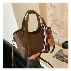Stylish brown PU leather women's tote bag with shoulder strap and cute charm for daily commute.