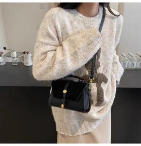 Detailansicht der schwarzen Wildleder- und Lederumhängetasche mit elegantem Griff und Gold.