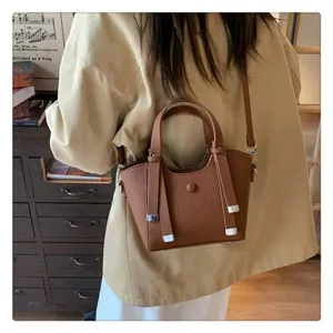 Detail shot of the stylish brown textured leather bucket bag worn across the shoulder indoors.