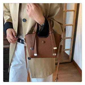 Close-up detail shot of a stylish brown leather shoulder handbag held by a model nicely.