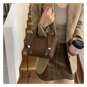 Stylish brown tote bag detail showing premium leather texture, dual handles and chic metal accent.