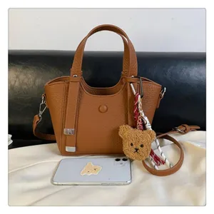 Brown PU leather tote bag with top handles, crossbody strap and cute bear keychain charm.