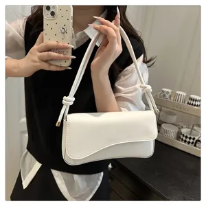 Close up detail of minimalist white shoulder underarm bag with stylish knotted strap design.