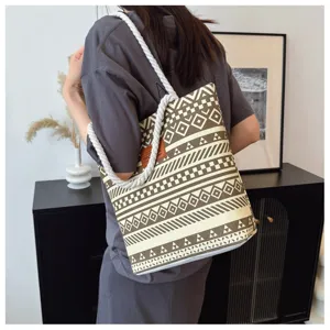 Detailed view of the canvas tote bag showing geometric print, rope handle, and fabric texture.