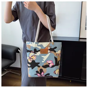 Detailed view of canvas tote bag featuring camouflage pattern and colorful butterfly prints.