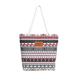 Detailed view of canvas tote bag featuring geometric print, rope handles and brown patch.