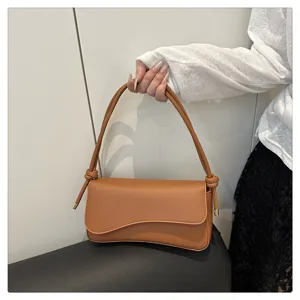 Detailed shot of trendy brown women underarm shoulder bag, chic asymmetric flap design chic bag.