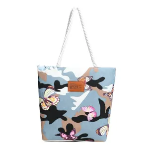 Detailed view of the canvas tote bag featuring a stylish blue camouflage butterfly print and handles.