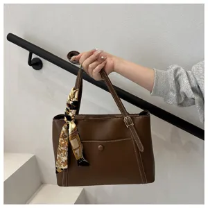 Detail view of the elegant brown commuter tote bag with a chic silk twilly scarf decoration.
