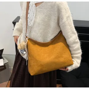 Detailed view of the brown suede hobo shoulder bag with cozy knit sweater and cute charm.