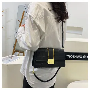 Dettaglio di una borsa a tracolla nera con stampa coccodrillo e chiusura dorata.