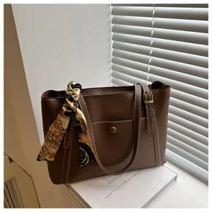 Detail view of the brown leather tote bag featuring a chic baroque printed twilly scarf accessory.