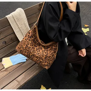 Detail shot of a retro leopard print shoulder bag on a wooden bench with knit scarf.