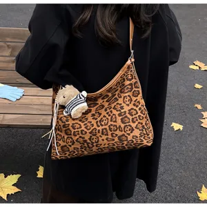 Detailed shot of a stylish leopard print shoulder bag with a cute plush pendant outdoors.