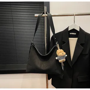 Black slouchy shoulder bag detail shot, large capacity suede hobo bag with cute dog pendant.