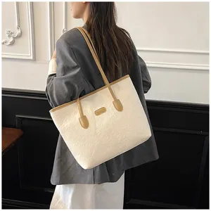 Detail view of the elegant cream tote bag showcasing embossed patterns and durable leather straps.