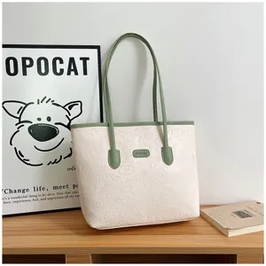 Detail view of the elegant beige embossed tote bag with green handles for daily commuting style.
