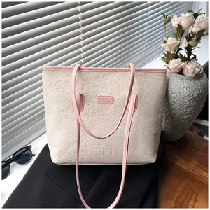Detailed view of beige tote bag with pink straps, debossed pattern and stylish design.