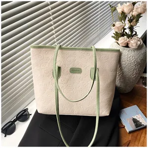 Detail view of beige tote bag with embossed cartoon patterns and green straps for daily commute.