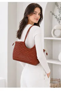 Vue détaillée du sac bandoulière en cuir tressé marron vintage porté par le mannequin.