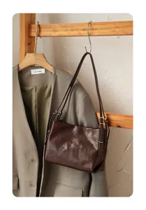 Detailed shot of dark brown leather shoulder bag, showing fine texture and metal hardware.