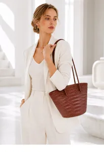 Close-up detail of the brown leather woven bucket bag in a bright modern indoor setting.