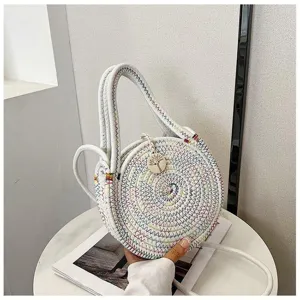 Detailed view of round woven crossbody bag with colorful thread accents and cute wooden pendant.