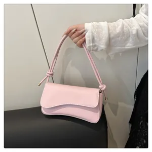 Detailed view of a chic pink baguette shoulder bag with stylish knotted straps and curve flap.