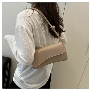 Close-up showcase of fashionable beige leather underarm shoulder bag with unique knot strap.