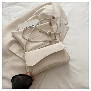 Minimalist cream shoulder bag detail, stylish underarm purse with knotted strap design.