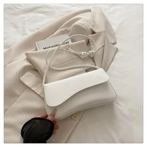 Detail shot of stylish white underarm bag with chic knotted strap and flap design for women.