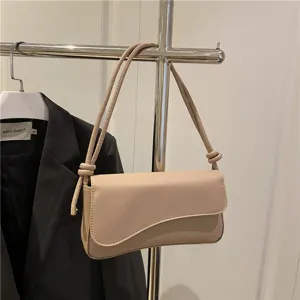 Chic beige shoulder underarm bag for women, trendy curved flap design with stylish knotted straps.