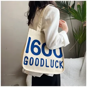 Canvas tote bag detail view, stylish casual shoulder bag with blue letter print design.