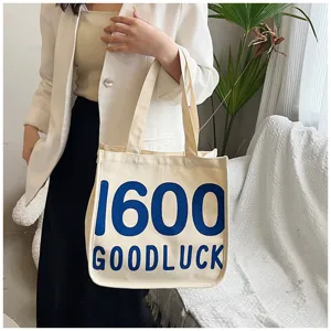 Detailed view of the casual canvas tote bag with blue letter print and shoulder straps for daily use.