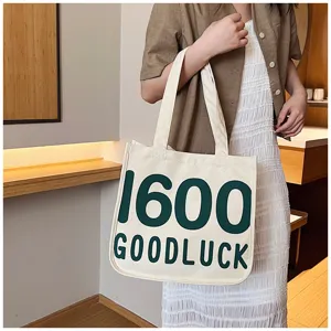 Detailed view of the casual canvas tote bag featuring green printed text, durable shoulder straps.