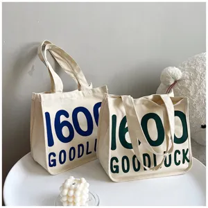 Canvas tote bag detail view, casual shoulder bag with letter print and double handles.