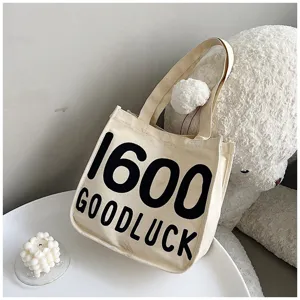 Close-up detail of the canvas tote bag with letter print, set in a cozy room decor.