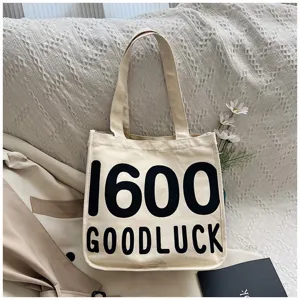 Close up detail view of canvas tote bag featuring large black typography print 1600 goodluck.