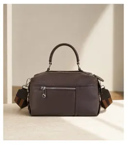 Detail view of dark brown leather top handle handbag showcasing premium texture and zipper.