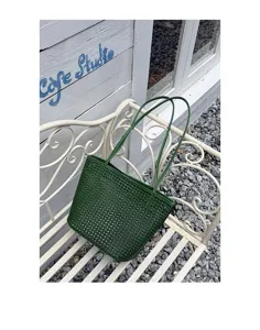 Dark green woven leather tote bag detail showing texture, casual minimalist shoulder style.