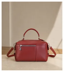 Red leather handbag detail shot highlighting fine texture, front zipper pocket, handle.