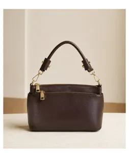 Detailed view of the brown leather top handle bag, showing fine texture and golden hardware.
