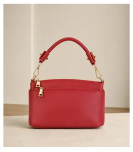 Red leather top-handle crossbody bag detail, gold hardware and double zipper close-up view.