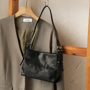 Minimalist black leather shoulder bag with double straps and metal buckle for daily commute.
