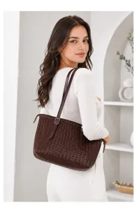 Detail view of the stylish dark brown woven leather shoulder bag worn by the model.