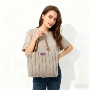 Vista dettagliata della borsa in peluche soffice con righe verticali e comodi manici marroni.