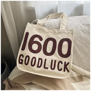 Close up detail shot of canvas tote bag featuring clear brown letter print and soft fabric.
