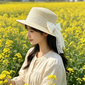 Detail view of a stylish women straw hat featuring delicate white lace and a elegant side bow.