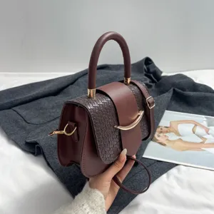 Detailed view of a dark brown woven leather shoulder bag with top handle and metal clasp.