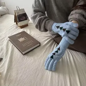 Detailed view of blue knit winter gloves with tree embroidery, warm long cuff design.